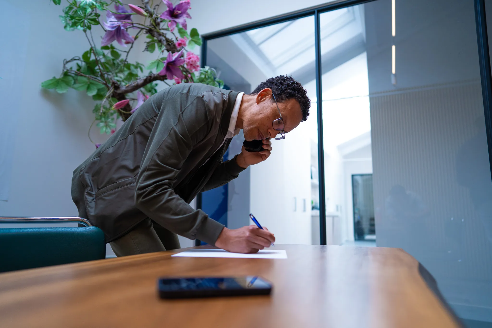 Auditor aan vergadertafel, telefonerend en aantekeningen makend